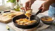 Hands flipping cheesy chicken wraps in a skillet on the stove.